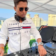 A focused shot of me at a rooftop party with the city skyline in the background. The location often inspires the music I play.