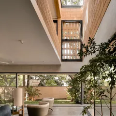 From the living room of the Debris Block House, the garden is always in view through floor-to-ceiling sliding glass doors. We brought a tree inside to further enhance the connection to nature and draw light down from a skylight above.