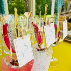 We believe garnishes are an art form. Here, we've used fresh dragon fruit and personalized initial tags clipped on with miniature clothespins for a beautiful, tropical, and bespoke cocktail presentation.