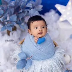 A precious baby boy wrapped in blue, nestled in a basket of soft clouds. This dreamy setup is perfect for a celestial or "Twinkle Twinkle Little Star" theme.