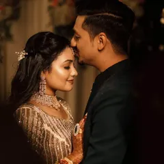 A tender moment between the couple during their Sangeet night. The groom places a gentle kiss on his bride's forehead, a quiet moment of affection amidst the grand celebration.