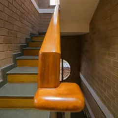 A close-up of the custom-shaped teak wood handrail on the staircase at Audumbara, designed to be both beautiful and comfortable to the touch.