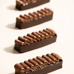 A minimalist shot of piped chocolate bars for Morde. The clean composition and lighting focus entirely on the texture and form, showcasing the chocolate itself as the hero.