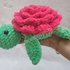 A 10-inch rose turtle made with plush yarn. The shell is crafted to look like a big pink rose, and the body is a cheerful green.