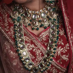 Another perspective on the bride's stunning jewelry set. This detailed photograph captures the way the heavy necklaces lay, showing the beautiful combination of polki and green beads that complete her bridal look.