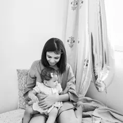 A quiet moment between a mother and her baby, captured in classic black and white. The number '1' balloon in the background marks her special milestone.
