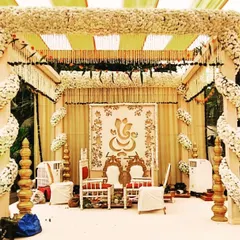 This white floral Vidhi Mandap gives a pure, sacred, and peaceful feeling. The pillars are wrapped in white flowers, and a Ganesha motif in the background adds a divine touch to the setup.
