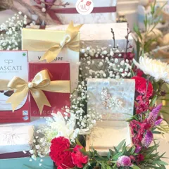 A close-up of our chocolate-loaded hamper, showcasing a variety of gourmet chocolates and treats, elegantly wrapped and surrounded by fresh flowers.