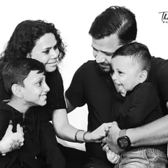 A candid family moment captured in the studio. Using a black and white format helps focus on the pure joy and interaction between parents and their children, creating a timeless memory.