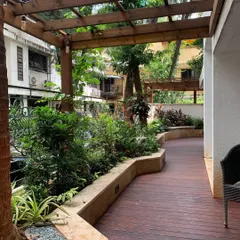 A beautiful, curved pathway made of wooden decking, flanked by raised planters, guides you through this lush ground-floor garden.