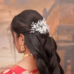 A closer view of this elegant bridal hairstyle. The delicate, crystal-like hair accessory adds a touch of modern sparkle to the classic braided look.