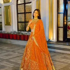 This shot showcases the beautiful gold detailing on the orange lehenga. It's paired with a simple gold choker, letting the outfit be the star.