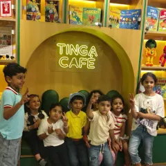 A group of happy kids flashes peace signs while sitting in the cozy booth at Tinga Cafe.