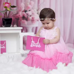 Pretty in pink for her Barbie-themed photoshoot. This little girl looks so sweet and gentle holding her Barbie bag in our floral studio setting.