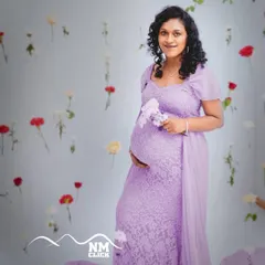 Our 'life-in-bloom' theme is a favorite among expecting mothers. Here, we used a backdrop of delicate hanging flowers to create a dreamy and ethereal portrait, perfectly complementing the soft lavender lace gown from our studio collection.