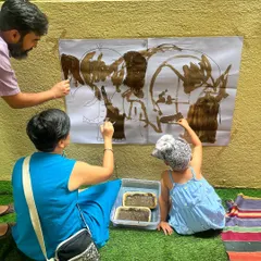 I believe play is a powerful way for families to connect. Here, parents and a child work together on a large-scale mud painting, turning a simple art activity into a memorable bonding experience.