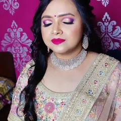 The soft, side-swept hairstyle complements the bold makeup and the intricate details of her pastel-colored lehenga.