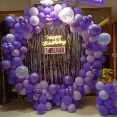 A beautiful purple-themed birthday party with a full circular balloon arch, a silver sequin backdrop, and a neon sign for Shreenika's celebration.