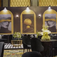 Another view of the lounge, showing the black and white checkered rug, sequined tabletops, and the striking abstract art backdrop, all contributing to the chic and modern vibe.