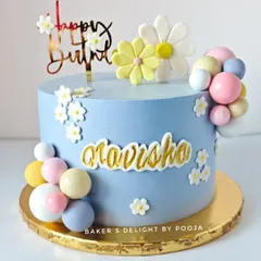 A beautiful birthday cake in soft pastel blue, decorated with daisies and colorful chocolate spheres. This design is sweet, cheerful, and perfect for a 9th birthday.