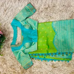 A striking contrast of a seafoam blue embroidered blouse with a parrot green silk saree. The custom tassels on the saree border tie the colors together.