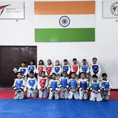 A formal group photo of the sub-junior training camp attendees, all in their sparring gear, in front of the Indian flag.