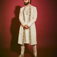 This regal look, inspired by Ranveer Singh, features a layered ivory sherwani, textured kurta, and pearl accessories. I can create this entire ensemble for your wedding day.
