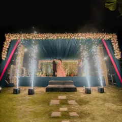 The couple shares a private moment on a beautifully decorated stage, framed by sparklers. This wide shot captures the scale and romance of their outdoor celebration.