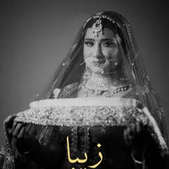 A timeless black and white portrait of the bride. The name "Zeba" is elegantly written, and the focus is on her holding the edge of her veil, creating a classic, poignant look.