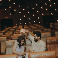 Laughter fills the empty theatre as the groom playfully tips a popcorn bucket. This candid shot captures the fun and spontaneity that makes each love story unique.