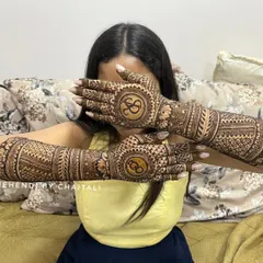 A popular pose to showcase engagement mehendi. This design features the couple's initials, 'S' and 'S', inside circular frames on the back of the hands.