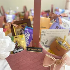 A toast to the bride's tribe. This quilted velvet basket is filled with goodies, including a personalized tumbler, chocolates, and a custom tag featuring the wedding hashtag, #PKKISHAADI, making it a truly personal thank you gift.