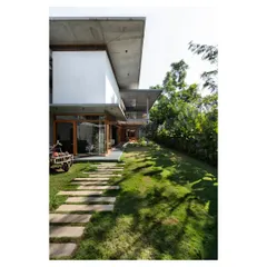 The House of Canopies, where bold cantilevered concrete roofs provide shelter while framing views of the garden. A simple stone path set in the lawn blurs the line between the built structure and the landscape, inviting the outdoors in.