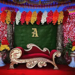 We offer simple yet elegant decor packages for events like engagements or naming ceremonies. This stage features a classic red and gold theme with a comfortable diwan, floral pillars, and a custom initial.