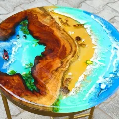 A closer look at a round ocean table where the beach meets the sea. I combined a natural wood slice with sandy textures, miniature palm trees, and vibrant blue resin to create a detailed tropical scene.
