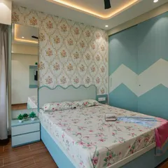 This charming bedroom combines a classic floral wallpaper with a playful chevron pattern on the sliding wardrobe. The scalloped headboard adds a touch of whimsy to the design.