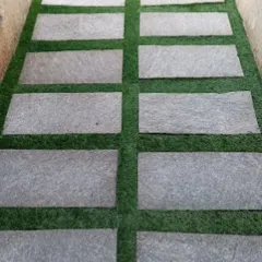 This is the same style of pathway, showing how the clean lines of the stone slabs contrast with the soft texture of the artificial grass. It's a practical and visually appealing hardscaping solution.