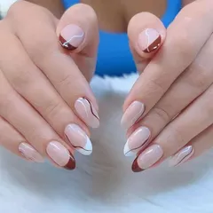 A sophisticated design with a mix of brown and white French tips, accented with delicate, abstract swirls.