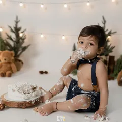 A first taste of birthday cake! This little one is covered in frosting and loving every second of his woodland-themed cake smash session.