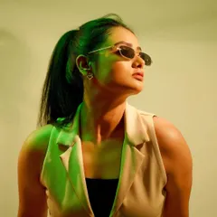 A modern portrait using a green gel light to create a cool, cinematic mood. The sunglasses and pose add to the high-fashion, edgy aesthetic.