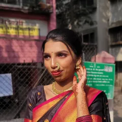 A radiant traditional Maharashtrian look, perfect for a wedding or festive occasion. The makeup features defined eyes, a classic nose ring (nath), and a subtle red lip that complements the black and red silk saree.