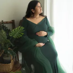 A moment of quiet reflection by the window. The natural light and surrounding greenery create a peaceful and organic setting for this solo maternity portrait.