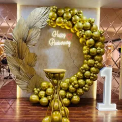 I design elegant and luxurious setups for milestone anniversaries. This first-anniversary decoration features a stunning all-gold chrome balloon ring, a custom "Happy Anniversary" neon sign, large marquee numbers, and decorative dried palm leaves for a modern, sophisticated look.