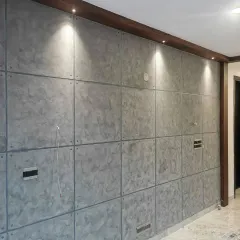 An industrial concrete-effect wall with panel detailing and embedded rivets, illuminated by spotlights to highlight its unique texture and design.
