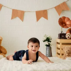 A happy baby boy during his milestone photoshoot. I use props like teddy bears and vintage items to create a charming and timeless look.