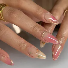 A beautiful example of a pink aura nail, enhanced with a delicate gold chrome frame and tiny dried flowers.