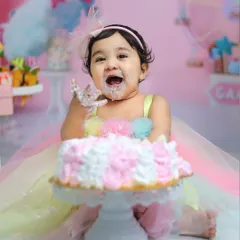 Pure joy and a mouthful of cake. This happy shot from a candy-themed cake smash session shows the fun and messy delight we aim to capture.