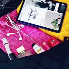 A closer look at the 'what's in my bag' flatlay, focusing on the tech and beauty products like my Apple Watch, perfume, and Pixi lip balm.