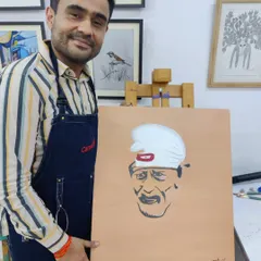 An adult student displays his finished portrait of Sai Baba, a piece created with focus and devotion in our studio.