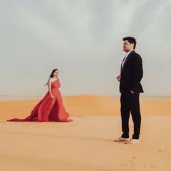 A dramatic pose in the Dubai desert. The contrast between the flowing red dress and the golden sand creates a powerful and visually striking image.